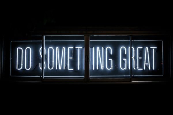 Leuchtschrift mit der Aufschrift ‚Do something great' vor dunklem Hintergrund