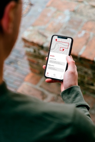 Pessoa a segurar um smartphone a mostrar uma rota na aplica&ccedil;&atilde;o
