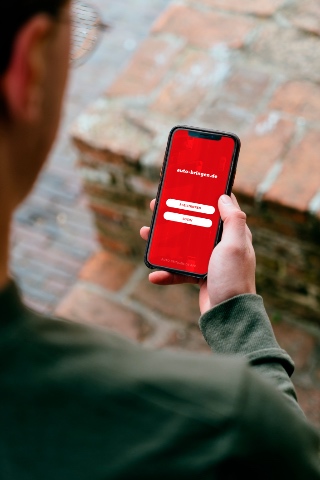 Pessoa a segurar um smartphone com a aplica&ccedil;&atilde;o auto-bringen.de aberta