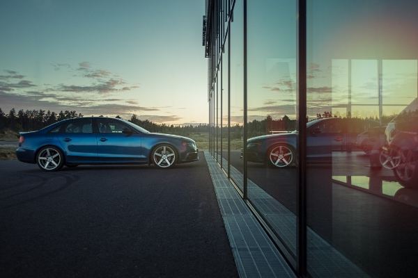 Berlina Audi azul frente a una fachada de cristal al atardecer