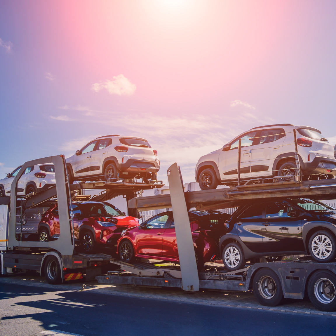 Autotransporter beladen mit mehreren Neuwagen bei Sonnenuntergang
